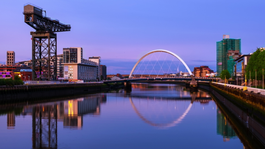 Glasgow, Scotland. View of Glasgow, UK landmarks - Finnieston Crane and Squinty bridge at sunset. Time-lapse with colorful twilight sky, panning video