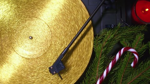 Fortuna gold, movie of retro-styled record player spinning golden vinyl. Cinemagraph. Christmas concept - spruce branch, lollipop and candle. Analog audio equipment, sound concept.