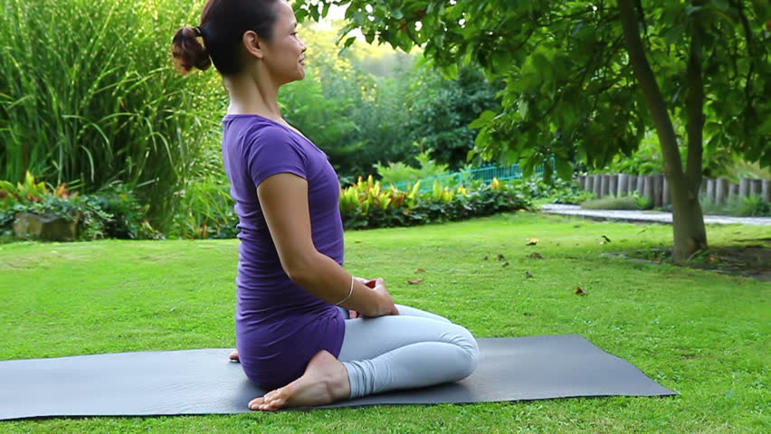 Woman is exercising yoga in the garden - Ground position - bent forward and