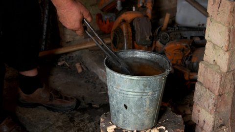 Blacksmith making horseshoe in workshop. Blacksmith put hot horseshoe in the water.