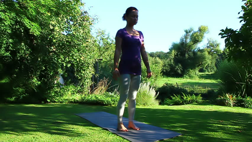 Woman is exercising yoga in the garden - Position on one leg