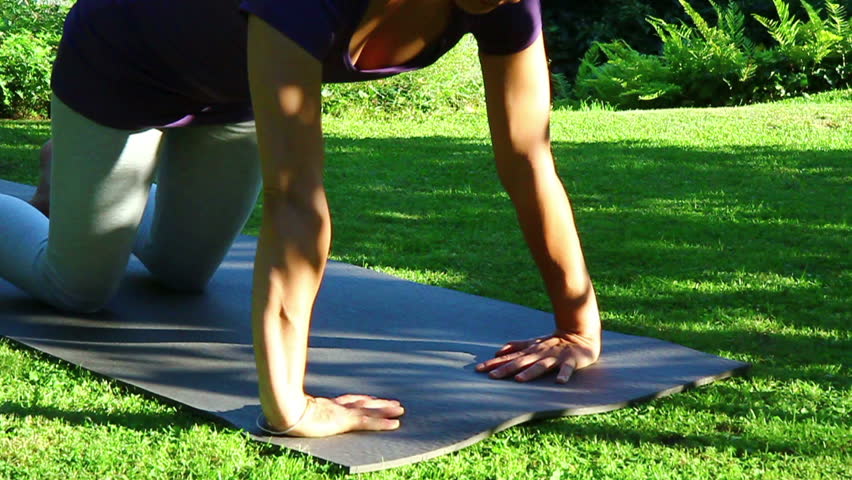 Woman is exercising yoga in the garden - Pushups position