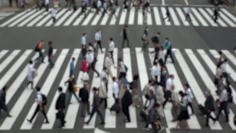 TOKYO, JAPAN : Aerial high angle view of crowd of people walking at zebra crossing in rush hour. Commuters at the street. Japanese city lifestyle, business and work concept. Slow motion blurred shot.