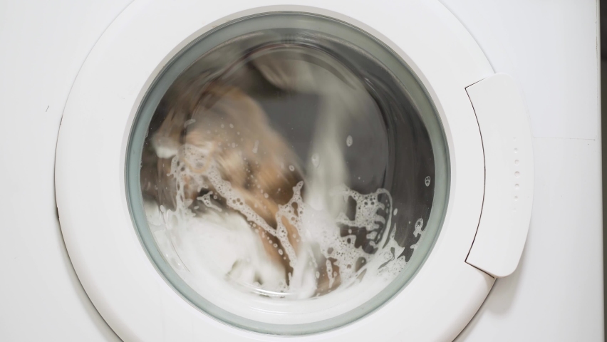 Washing clothing in domestic washing machine in home. Close-up video of spinning drum washing machine. Royalty-Free Stock Footage #1066336093