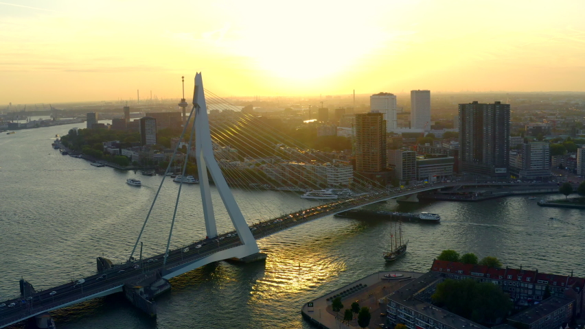Parallax shoot of Rotterdam heart - Erasmusbrug bridge and city center in background. Areal view of South Holland city scape during golden hour.