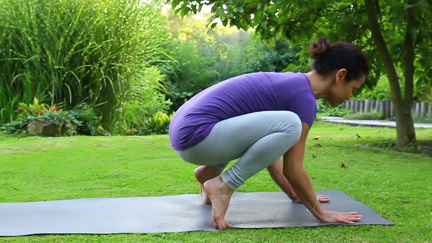 Woman is exercising yoga in the garden - Ground position - Jumping backwards