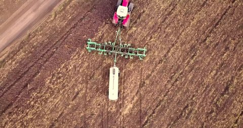 Aerial view of a tractor pulling a plow and an anhydrous tank of ammonia in a farmer's field. Heavy machinery during cultivation, work in the fields. Agricultural tractor in the field.