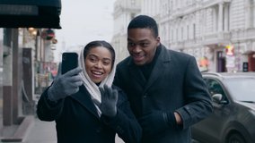 Modern reality. Outdoor portrait of young african american couple video calling to friends via smartphone, online communication, slow motion, tracking shot