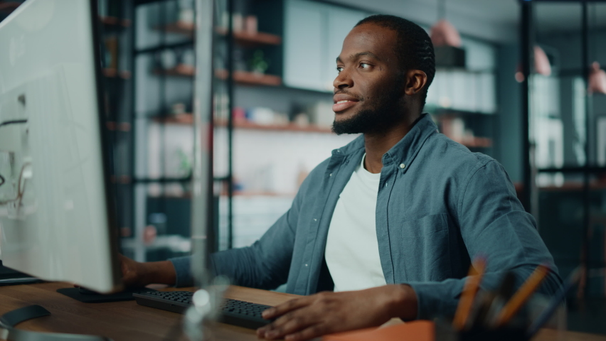 Handsome Black African American Specialist Working on Desktop Computer in Creative Home Living Room. Freelance Male is Working on a Finance Presentation Report for Clients and Employer. Royalty-Free Stock Footage #1066358689
