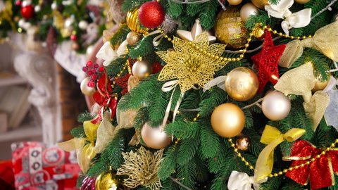 Closeup of glowing garland and golden baubles on decorated Christmas tree. Winter holidays background or backdrop