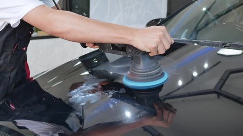 Professional polisher is polishing paint in car paint shop.