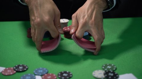 Man dealer or croupier shuffles poker cards in a casino on the background of a table, poker game concept
