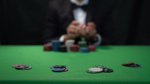 Man dealer or croupier shuffles poker cards in a casino on the background of a table, poker game concept