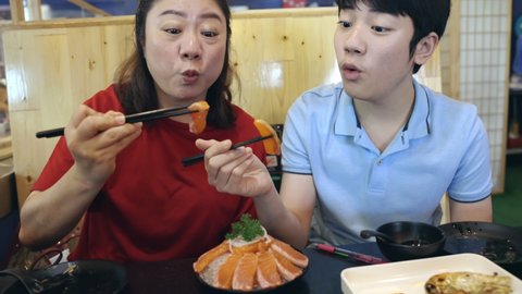 Asian Family visits a Korean grill restaurant , Eating 
Salmon Sushi with smile face. Travel to Korea concept