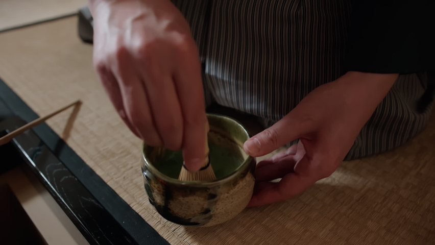 Cultural heritage of Japan: traditional Japanese tea ceremony. Tea master mixing matcha tea in chawan bowl with the use of special tools: chasen, chashaku, Chaki. One of the practices of Zen Buddhism | Shutterstock HD Video #1066369582