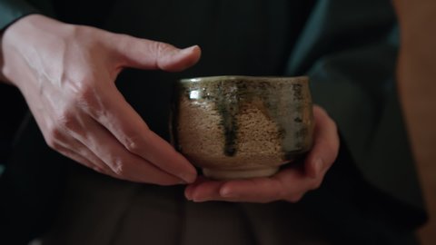 The tea master turning a chawan bowl with the prepared matcha tea  before handing it to a guest. Traditional Japanese tea ceremony chanoyu is a famous Japanese custom, art and Zen Buddhism practice
