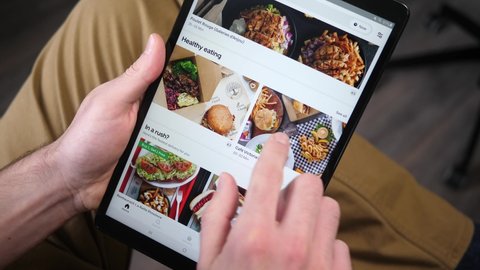 On the tablet browsing Uber eats app searching for something to eat. Many different menu of restaurants from nearby are presented to the user. MONTREAL CANADA JANUARY 2021