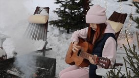 teenage girl playing guitar outside in the yard in winter