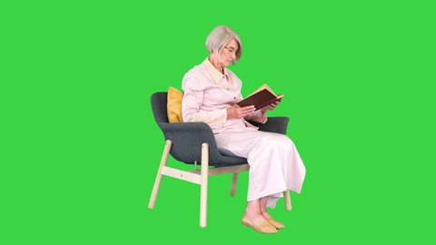 Smart senior woman reading a book emotionally on a Green Screen, Chroma Key.