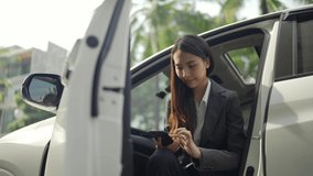 Video Slow-motion. Nice looking Asian businesswoman with white skin in black suit is chatting with a smartphone in her car on city streets.