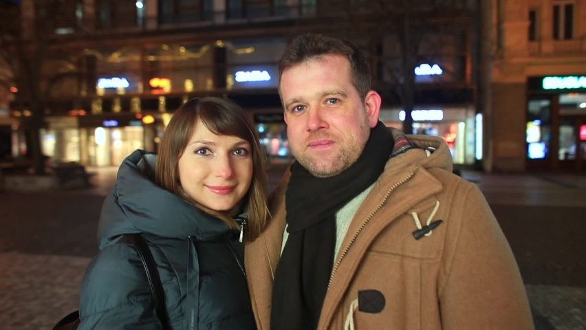 Portrait man and woman on evening street Prague. Meeting on date after dating site. They look at camera, smile. Calmness next to man. Camera movement.