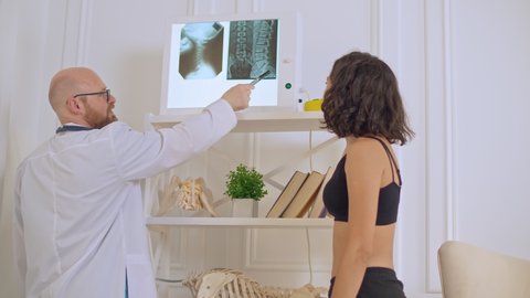 The Doctor Shows the Young Woman her X-ray, Evaluating the Patient's Condition in Order to Suggest Appropriate Treatment. Back Health
