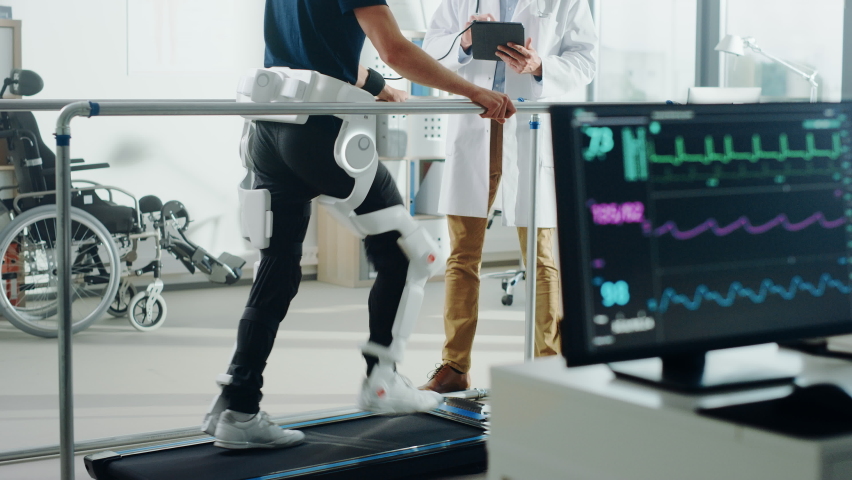 Modern Hospital Physical Therapy: Doctor Uses Tablet Computer, Disabled Patient Walks on Treadmill Wearing Advanced Robotic Exoskeleton. Computer Monitor Shows Physiotherapy Rehabilitation Activity | Shutterstock HD Video #1066412716