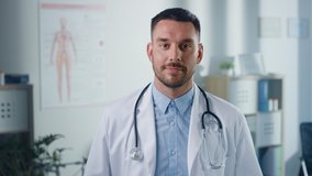 Portrait of Handsome Caucasian Medical Doctor Wearing White Coat and Stethoscope Crosses Arms, Standing in His Health Clinic Office. Successful, Confident Physician Looks at the Camera, Smiles