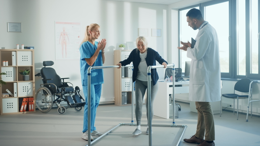 Hospital Physical Therapy: Portrait of Strong Senior Female Patient with Injury Successfully Walks Holding Parallel Bars. Physiotherapist, Rehabilitation Doctor, Help, Assist Disabled Patient | Shutterstock HD Video #1066412809