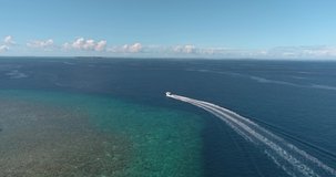 A drone flies over the sea in the Maldives, catching up with a white boat that rushes through the waves.	