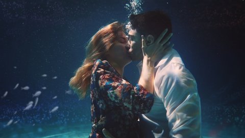 Cinematic shot of young carefree romantic loving couple is kissing with passion in ocean underwater during their honey moon vacation holiday. Concept of love, relationship,freedom, sensuality, fantasy