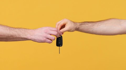 Close up cropped man male hands present give each other gift car keys isolated on yellow background studio. Birthday holiday concept. Copy space commercial advertisement Advertising workspace mock up