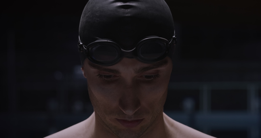 Cinematic shot of young professional male swimmer with swim cap is putting on goggles before to start practicing and training in swimming pool. Concept of sport, competition, victory, fitness, passion Royalty-Free Stock Footage #1066418488