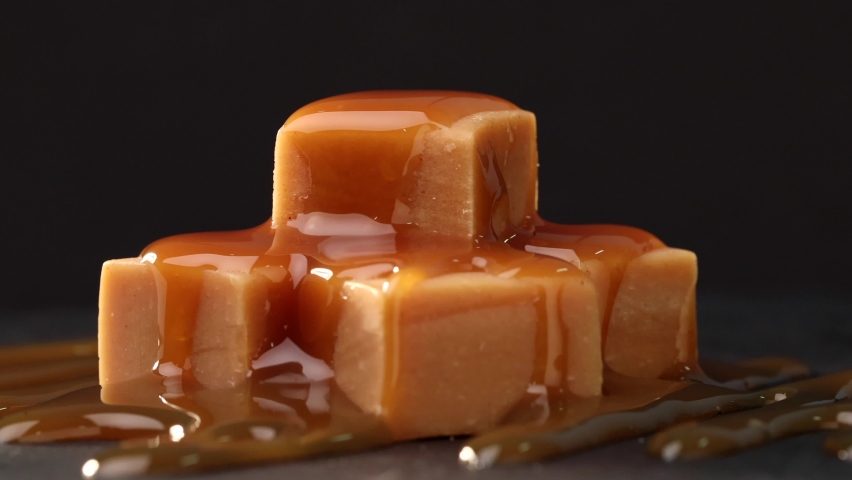 rotating caramel candies covered with melted caramel sauce close up on black background Royalty-Free Stock Footage #1066418536