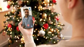 christmas, technology and holidays concept - close up of woman with smartphone having video with indian male friend call at home