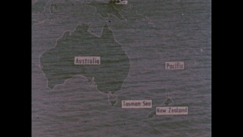 1950s: Map of New Zealand and Australia. Arrow and label appears over Tasman Sea on map. Arrows appear on globe between Japan, United States and New Zealand. Snow-capped mountains overlook valley.