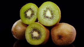 Kiwi fruit rotating on a black background in 4K. Close up of fresh and tasty kiwi, studio footage.