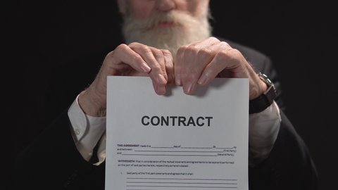Serious bearded businessman tearing paper with contract sign, bad conditions