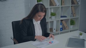 upset businesswoman looking at charts on desk