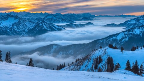 Sunset cloud movements with colored sky.A sea of fog is formed Above the clouds over. Flat surface. Cloudy mixed sunny day mix time lapse alps mountain pre alps germany austria, europe. Winter snow.