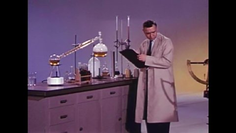 CIRCA 1950s - A man stands by a lab table and talks about making new synthetic fibers as a man in a lab coat carries out a test in 1958.