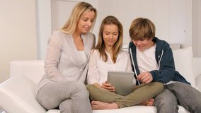 Mother and children relaxing in sofa with electronic tablet