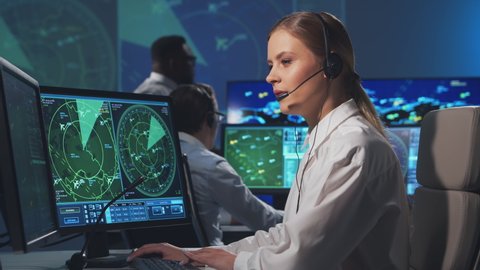 Workplace of the air traffic controllers in the control tower. Diverse team of aircraft control officers works using radar, computer navigation and digital maps. Aviation concept.