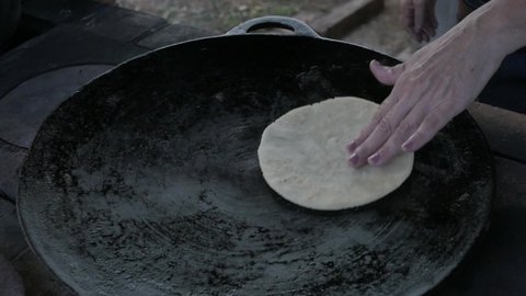 hands making a wheat tortilla in a pan a Costa Rican tradition to accompany a coffee
