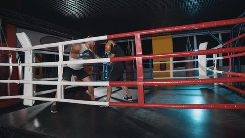 Lviv, Ukraine - 20 September, 2020: Boxing tournament. Two boxers are fighting in professional match. On ring are caucasian and multiracial fighters wearing gloves. Two men training at ring