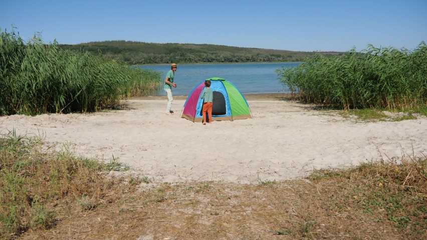 Funny child son and father quickly run around tent catch up playing touch and play tag game outdoor. Dad chasing kid having fun enjoy leisure activity laughing spend time together in local hike travel