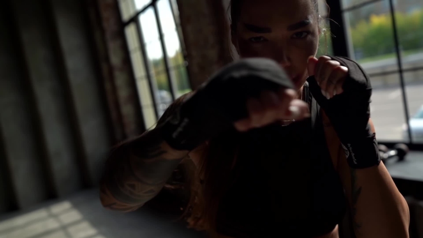 Close-up of a woman with long hair in a ponytail and hands in special boxing bandages. she's fighting the shadow. the camera is moving | Shutterstock HD Video #1066446370