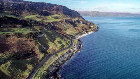 Northern Ireland, UK, Atlantic coast with cliffs. Causeway Coastal Route a.k.a Antrim Coast Road. One of the most scenic coastal roads in Europe. Aerial 4K video. Winter, sunrise light