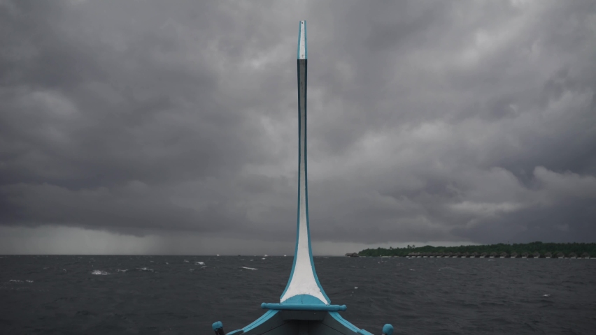 The bow of the ship in a storm swings in different directions against the background of a prolonged dark gray sky in the rain.