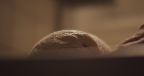 Chef slowly kneading traditional pizza dough in a restaurant kitchen. Close up, slow motion